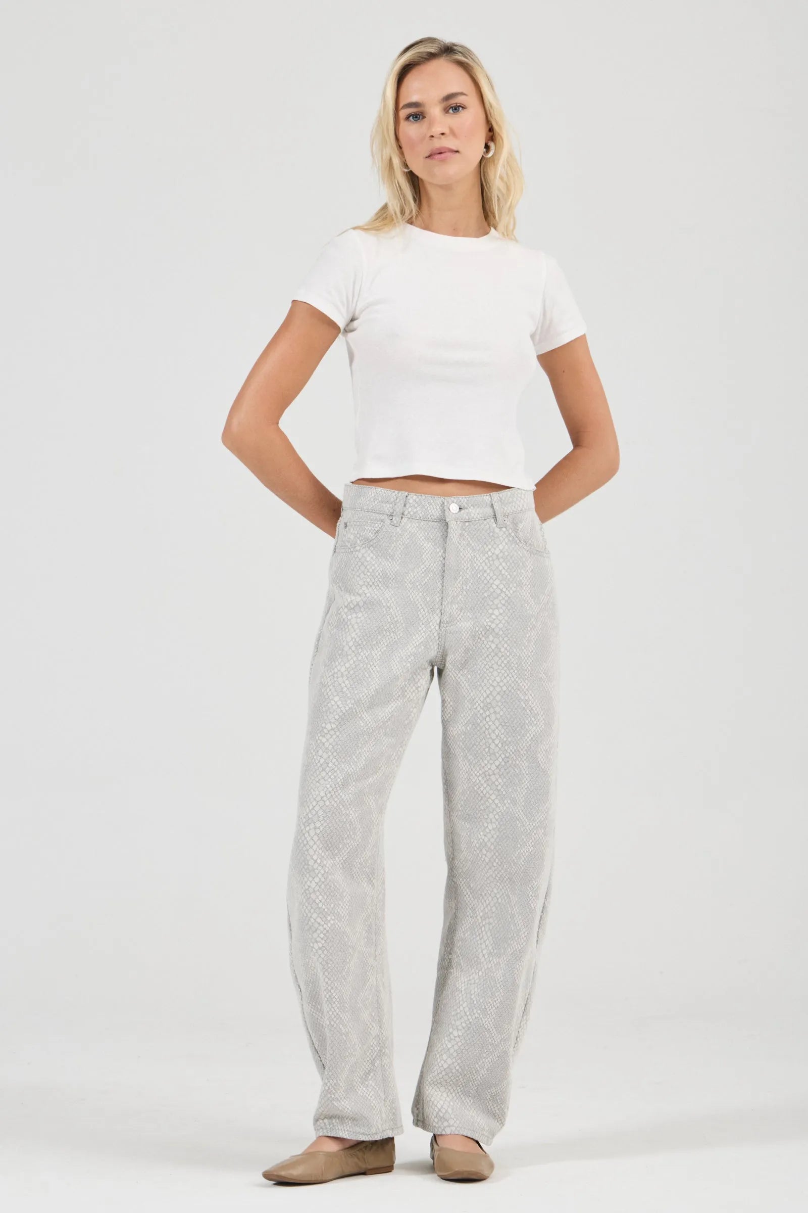 Woman wearing a white crop top and gray pants on a white background