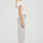 Woman wearing a white top and light gray pants on a white background