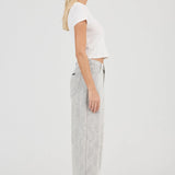 Woman wearing a white top and light gray pants on a white background