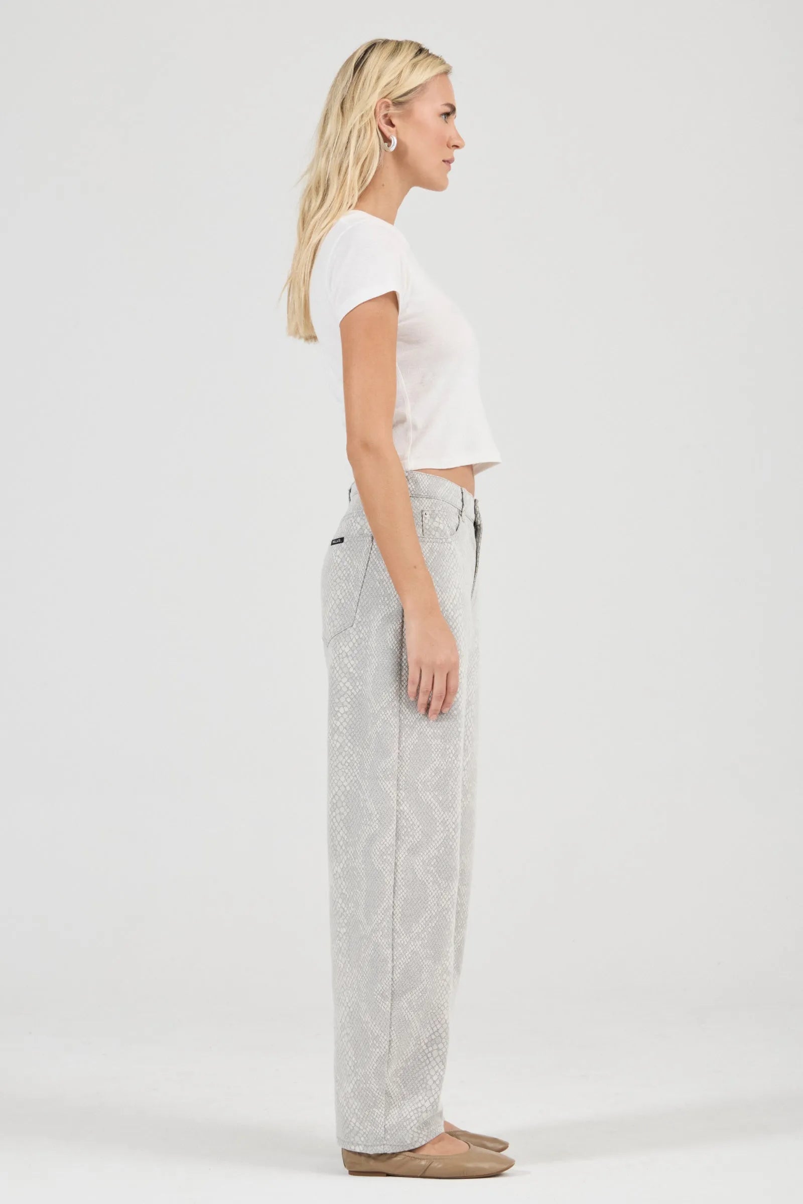 Woman wearing a white top and light gray pants on a white background