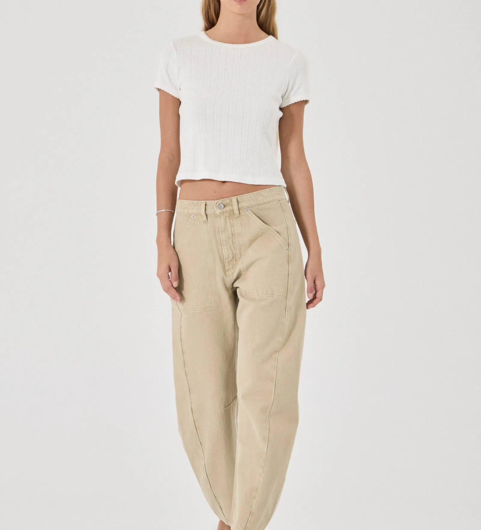 Woman wearing a white top and beige pants on a white background