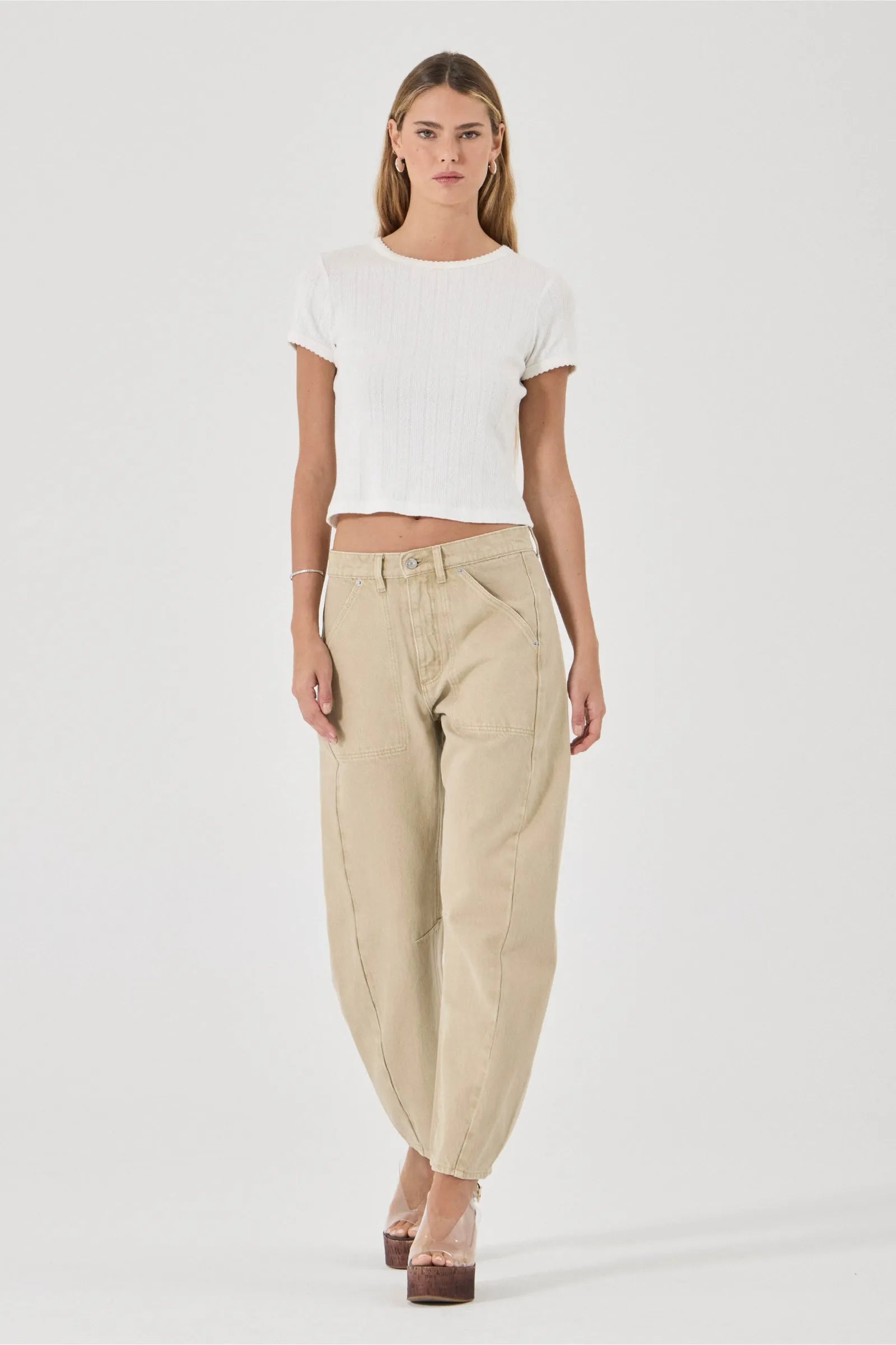 Woman wearing a white top and beige pants on a white background