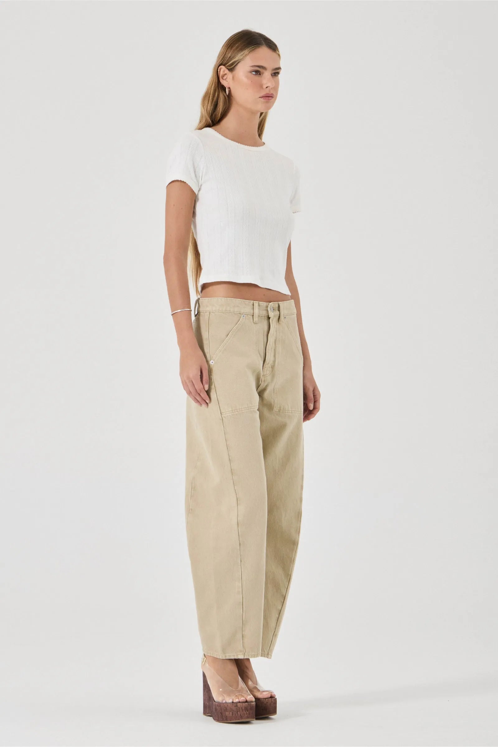 Woman wearing a white top and beige pants on a white background
