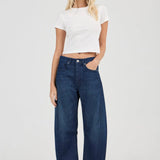 Woman wearing a white crop top and blue jeans on a white background