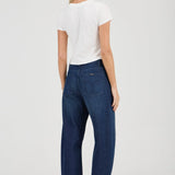 Woman wearing blue jeans and a white t-shirt on a plain background