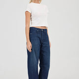 Woman wearing blue jeans and a white top on a white background