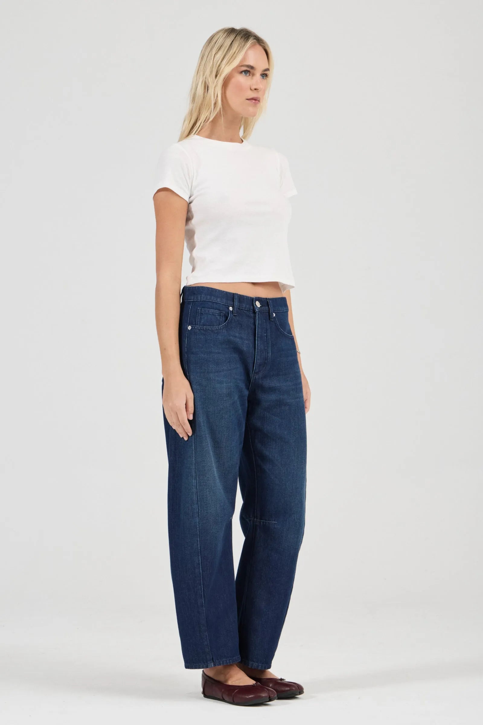 Woman wearing blue jeans and a white top on a white background