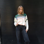 Person wearing a Printed Long sleeve Jersey and dark jeans standing against a black metal shutter.