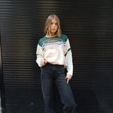 Person wearing a Printed Long sleeve Jersey and dark jeans standing against a black metal shutter.