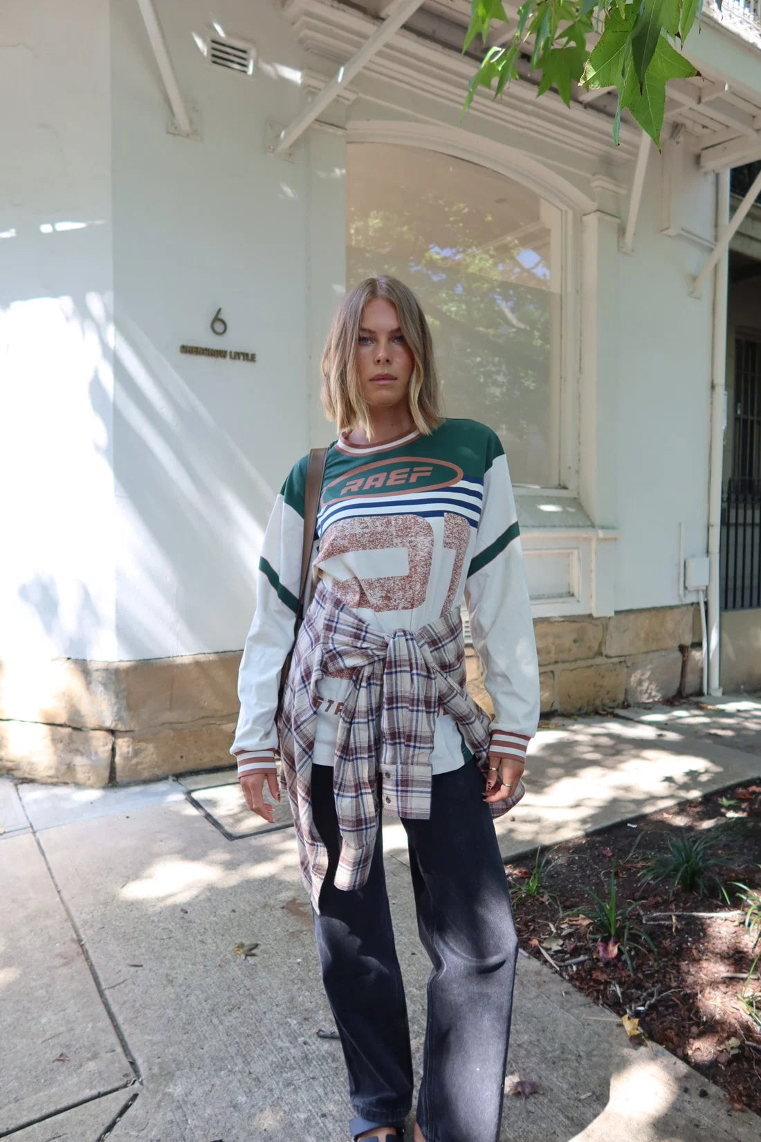Person wearing a Printed Long sleeve Jersey and dark jeans with plaid shirt around waiste
