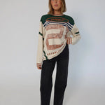 Woman wearing a patterned sweater and black pants on a white background