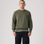 Man wearing a green sweatshirt and black pants on a plain background