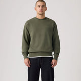 Man wearing a green sweatshirt and black pants on a plain background