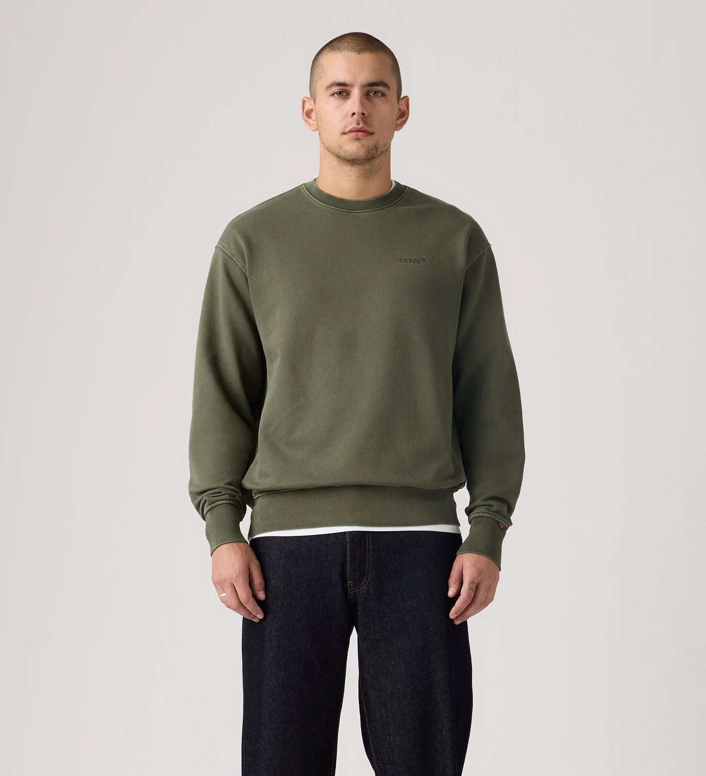 Man wearing a green sweatshirt and black pants on a plain background
