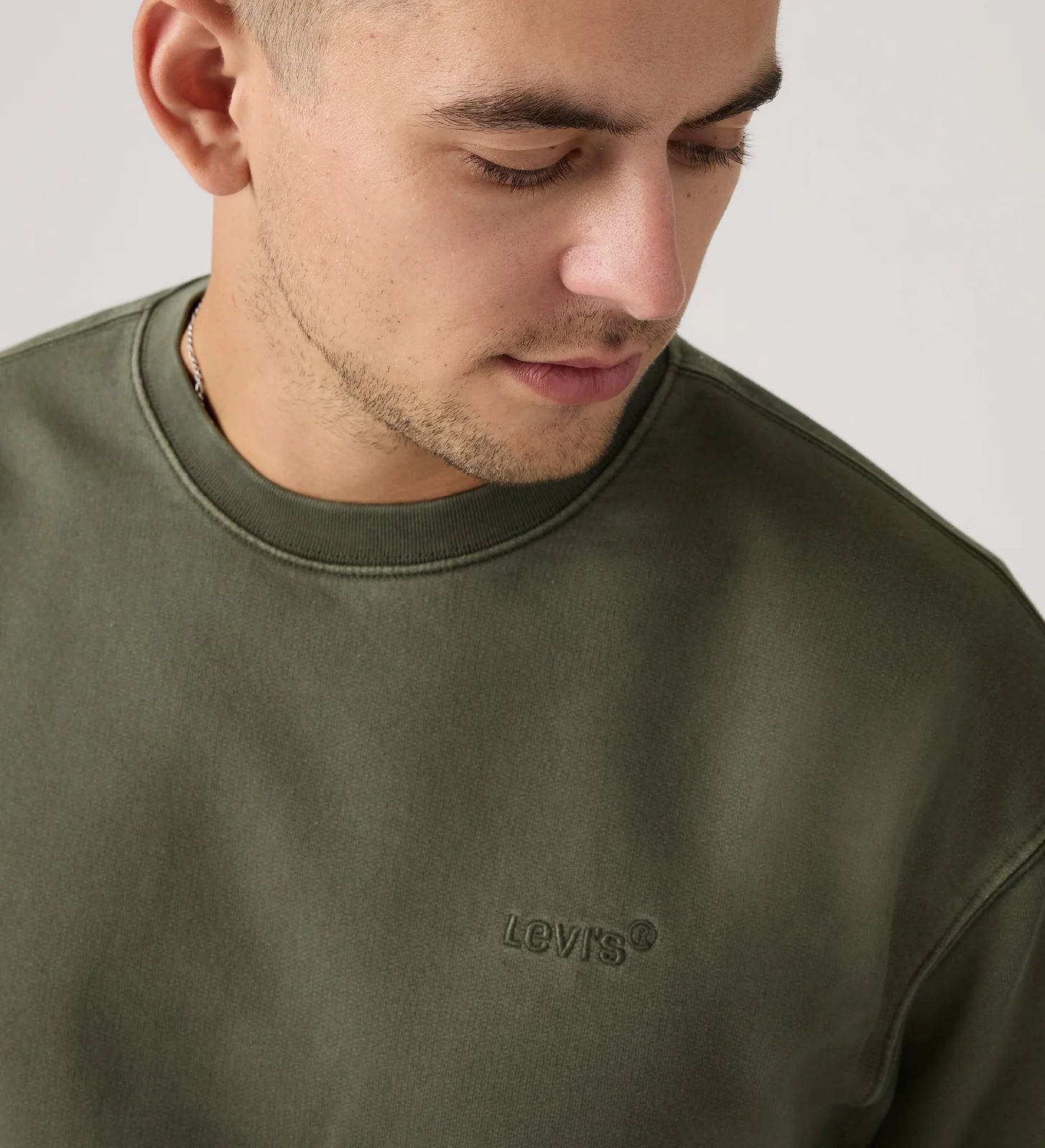 Man wearing a green Levi's sweatshirt against a plain background