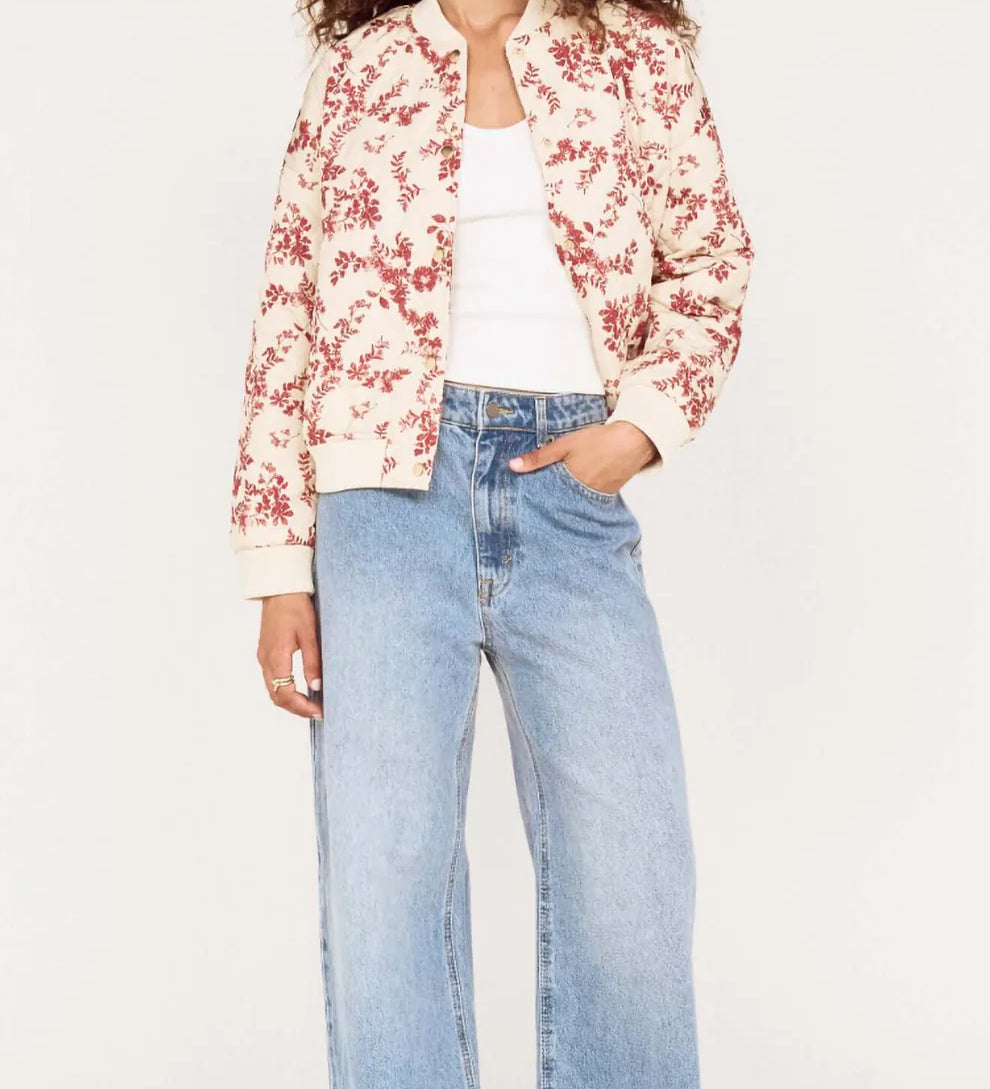 Woman wearing a floral jacket and blue jeans on a white background