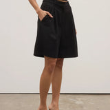 Person wearing a black skirt and black high-heeled shoes on a plain background