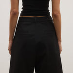 Person wearing a black t-shirt and black shorts on a plain background