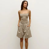 Woman wearing a beige strapless top and high-waisted shorts against a white background