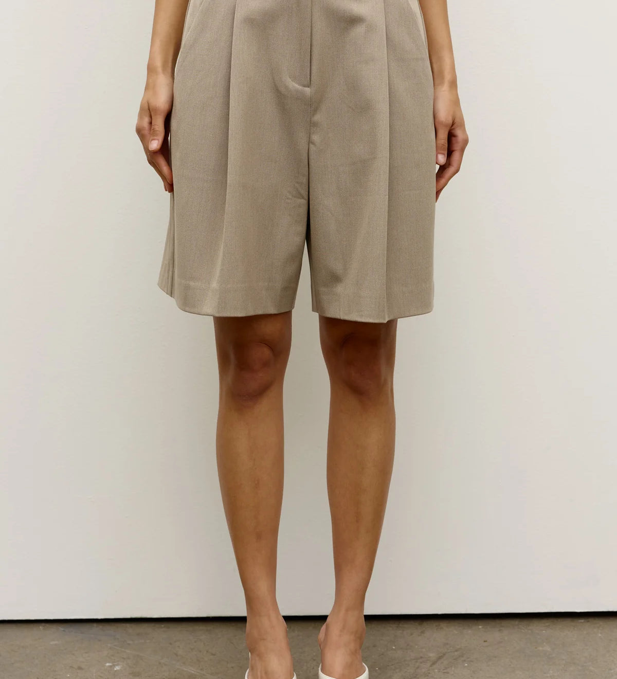 Person wearing beige shorts against a white background