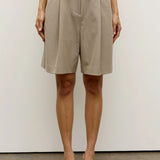 Person wearing beige shorts against a white background