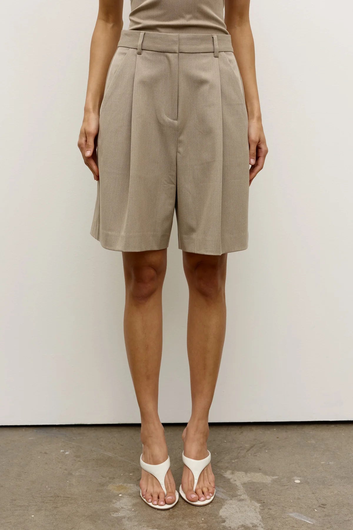 Person wearing beige shorts against a white background