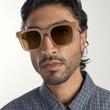 Man wearing brown sunglasses with a neutral background