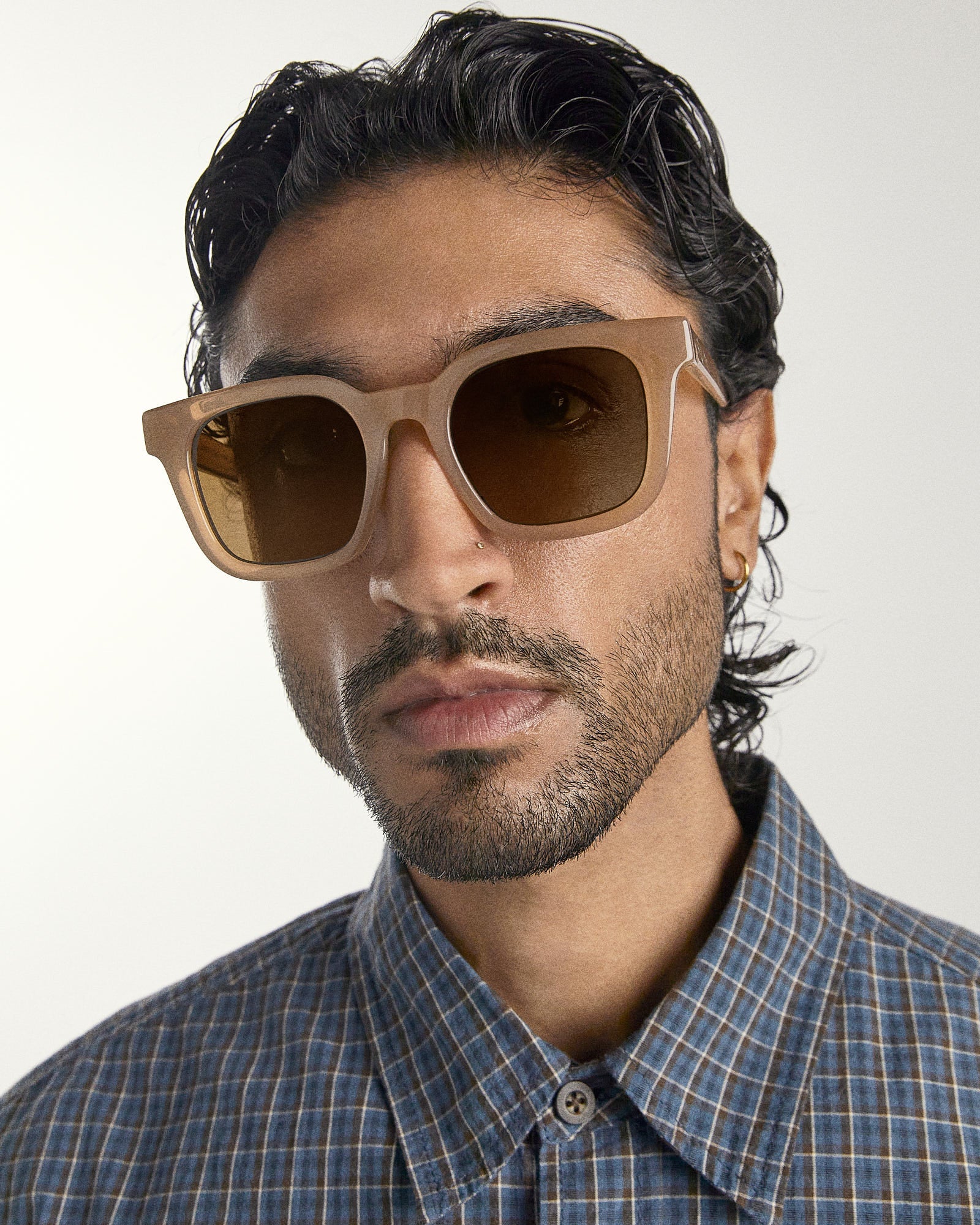 Man wearing brown sunglasses with a neutral background