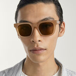Person wearing brown sunglasses with a neutral background