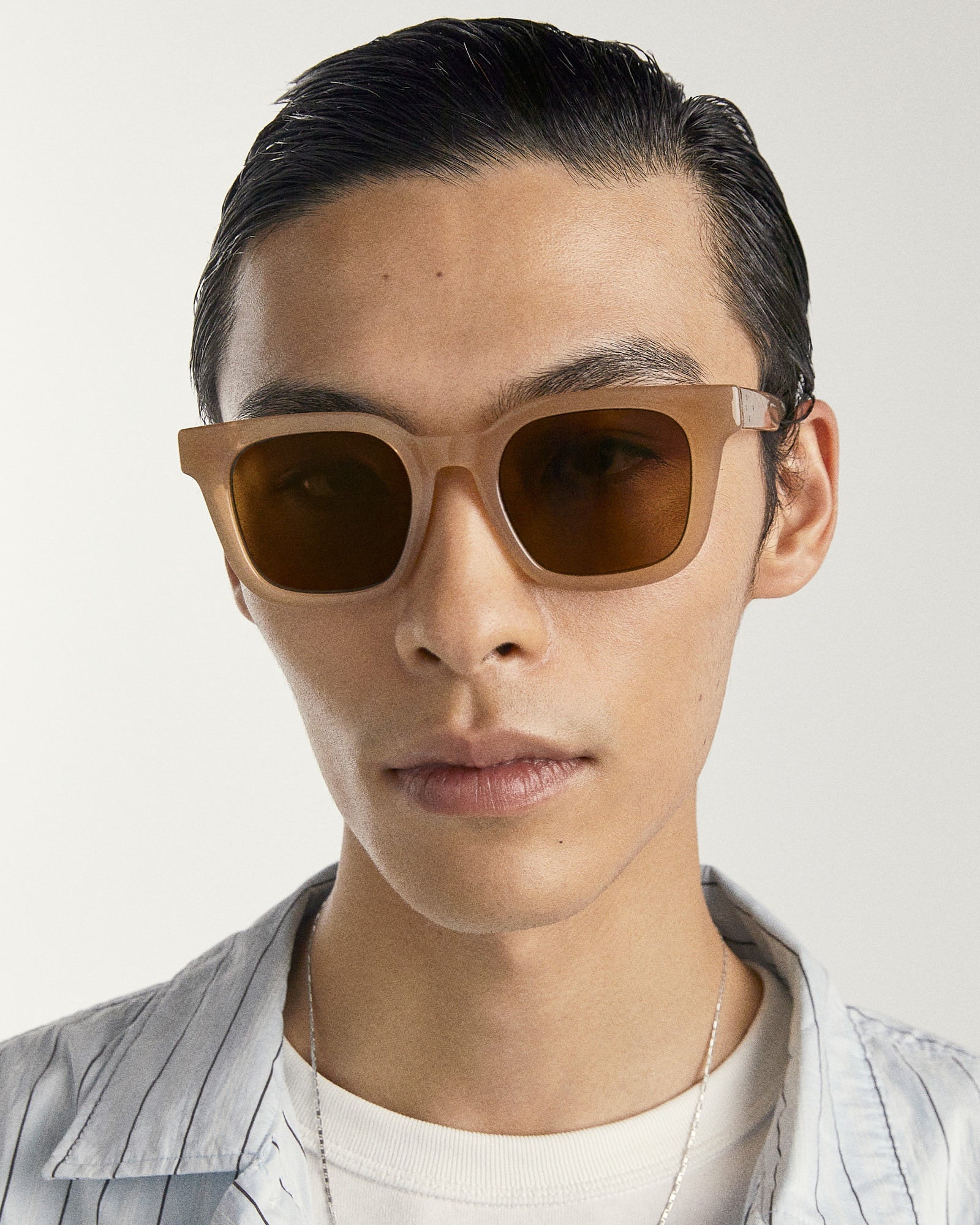 Person wearing brown sunglasses with a neutral background