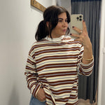 Person taking a mirror selfie wearing a striped sweater and jeans in a room.