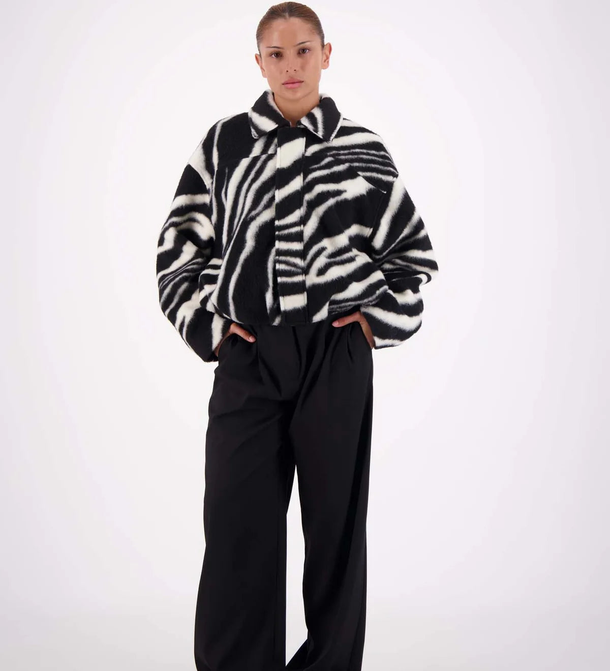 Person wearing a zebra-striped sweater and black pants on a white background