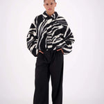 Person wearing a zebra-striped sweater and black pants on a white background