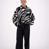 Person wearing a zebra-striped sweater and black pants on a white background