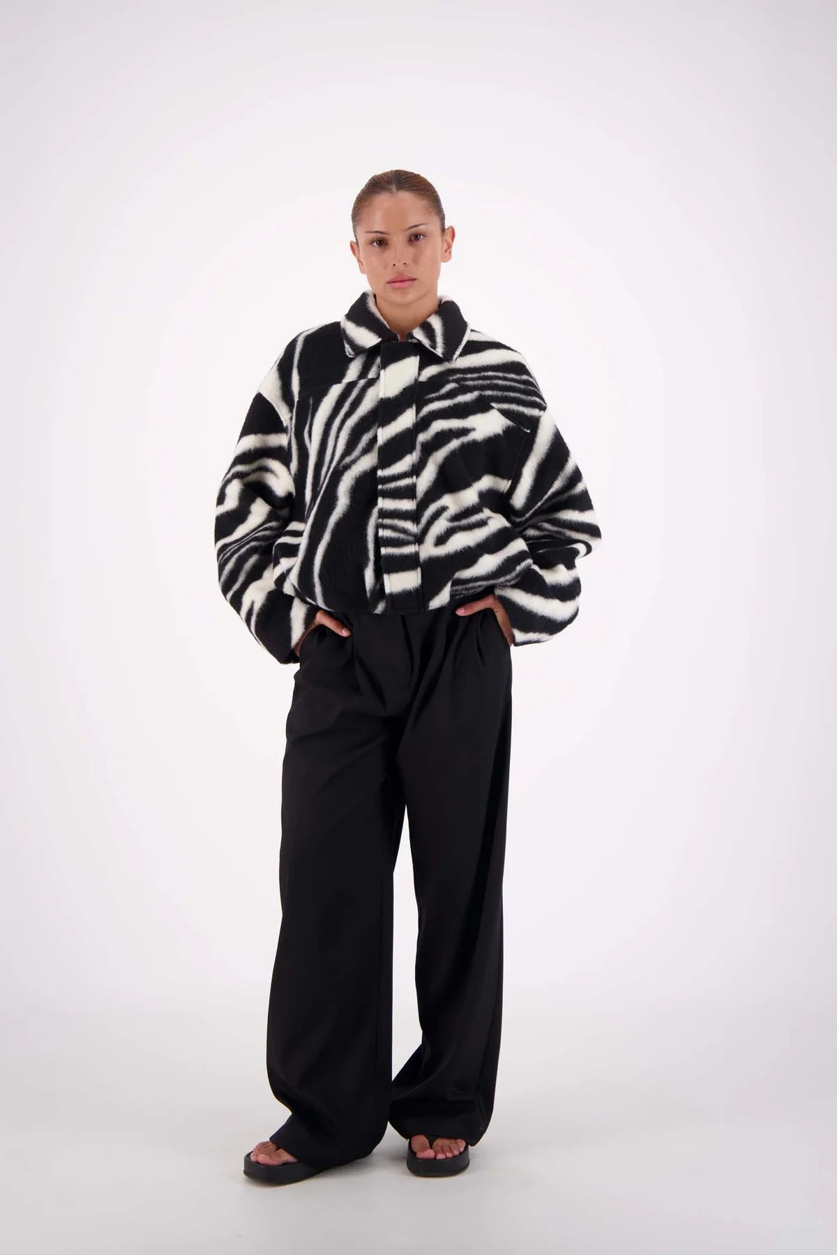 Person wearing a zebra-striped sweater and black pants on a white background