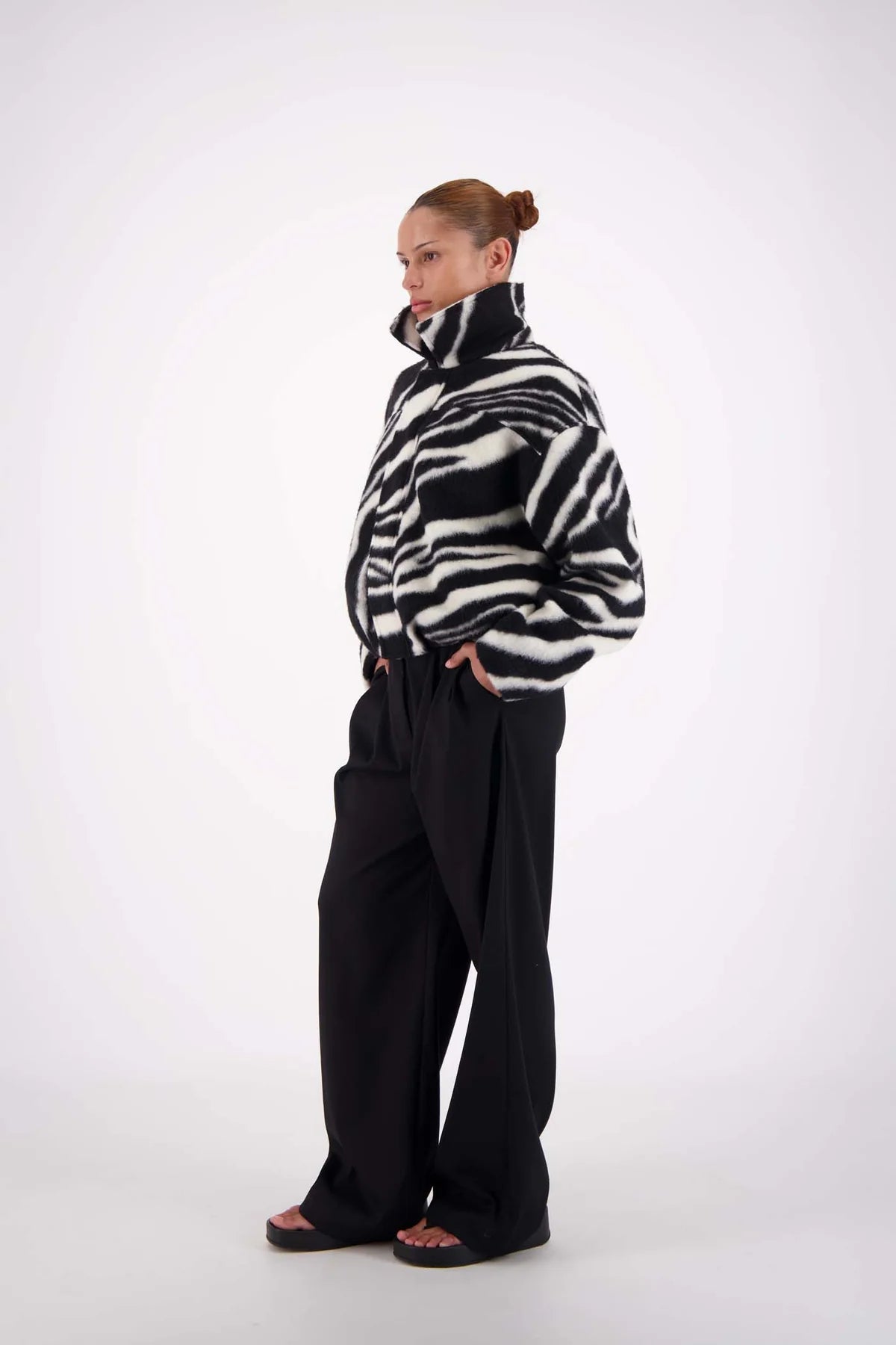 Person wearing a black and white patterned sweater with black pants on a white background