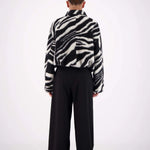 Person wearing a zebra-striped shirt and black pants on a white background