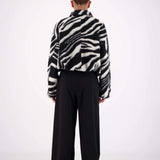 Person wearing a zebra-striped shirt and black pants on a white background
