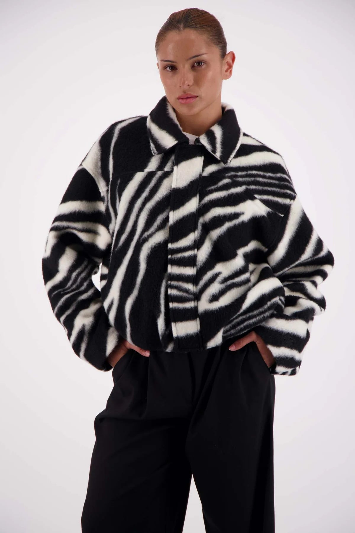 Person wearing a zebra-striped coat against a white background