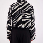 Person wearing a black and white zebra patterned jacket on a white background