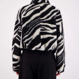 Person wearing a black and white zebra patterned jacket on a white background