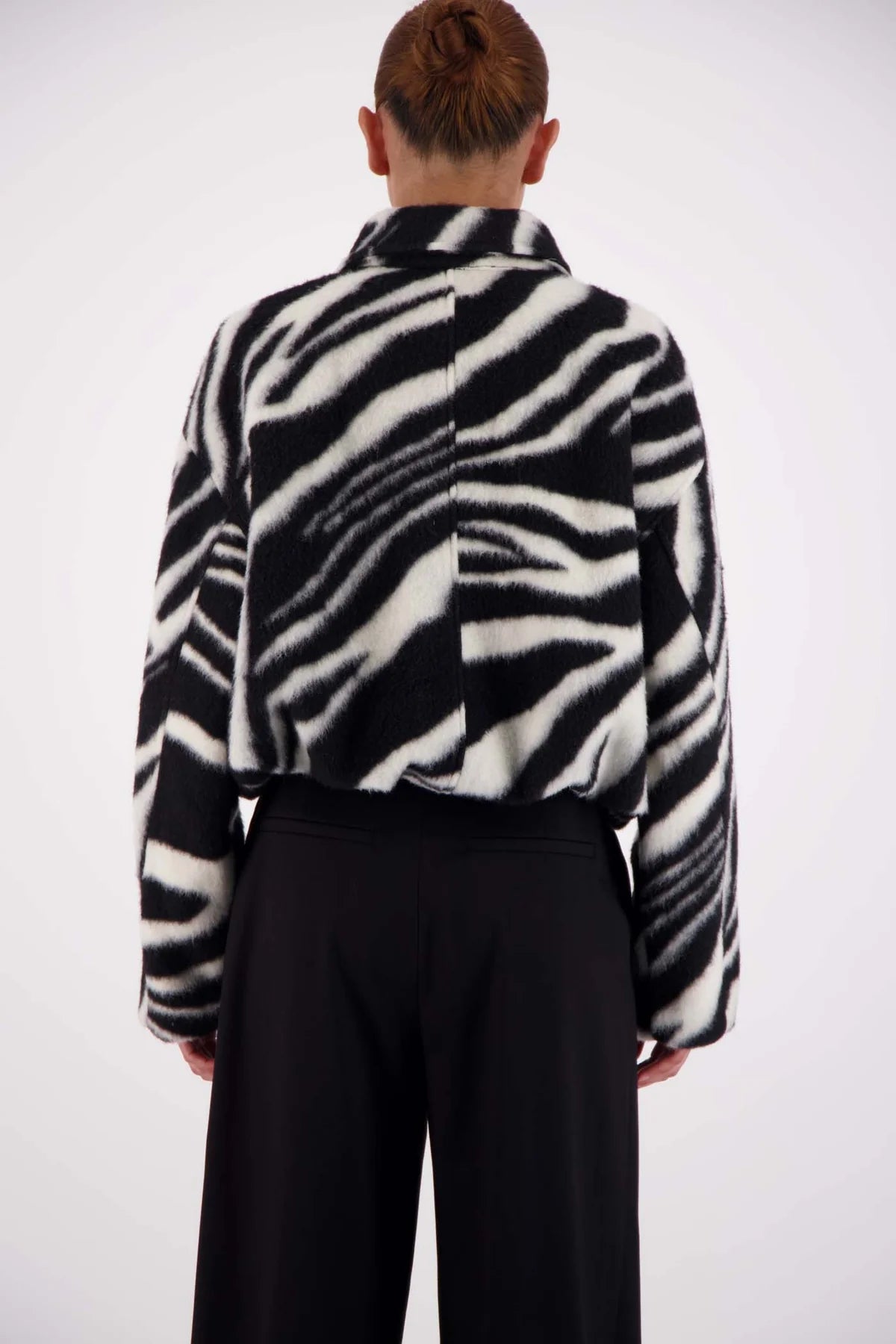 Person wearing a black and white zebra patterned jacket on a white background