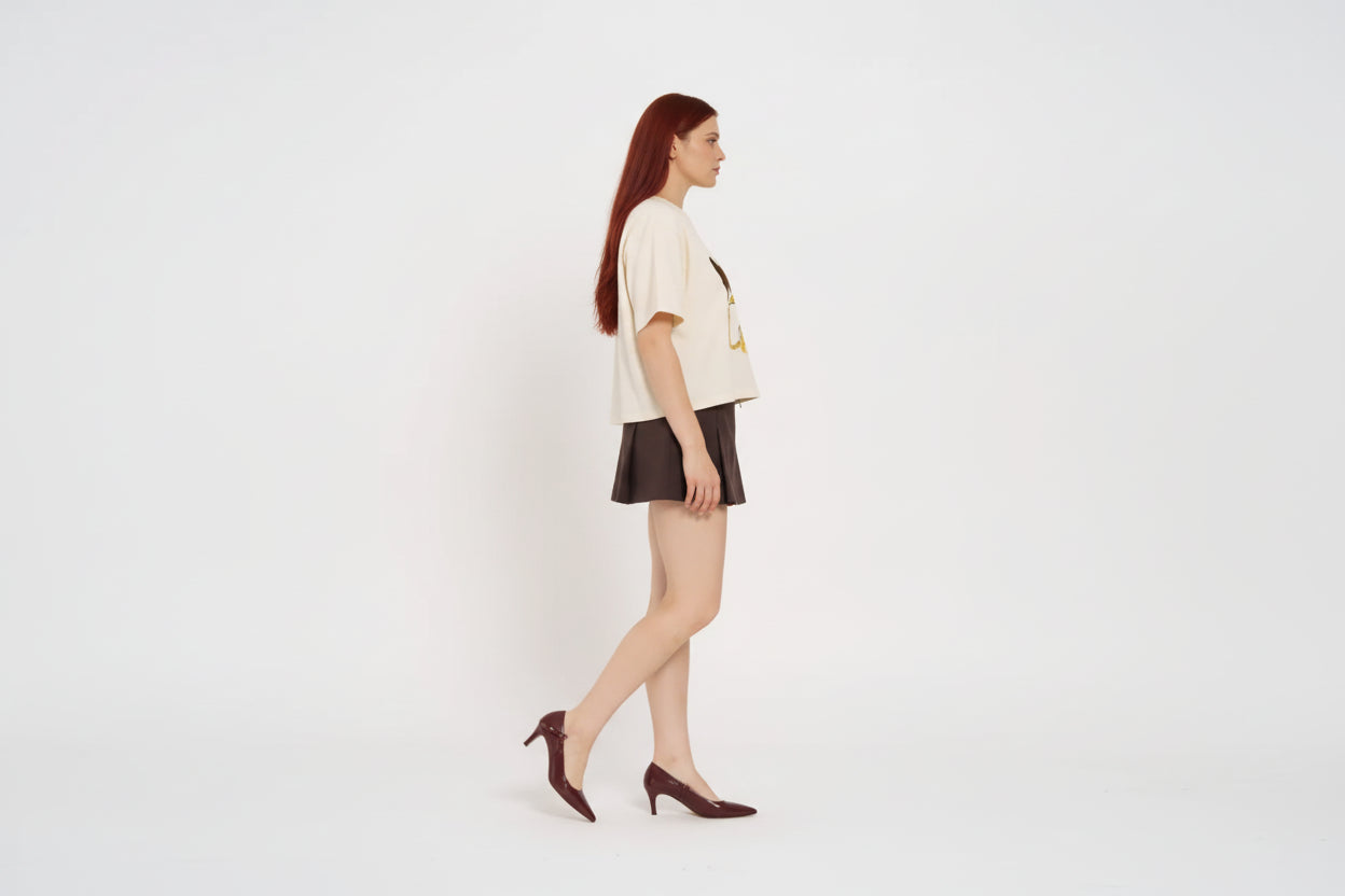 Woman wearing a cream t-shirt with 'MAKU' print and a brown skirt on a white background