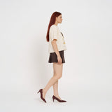 Woman wearing a cream t-shirt with 'MAKU' print and a brown skirt on a white background