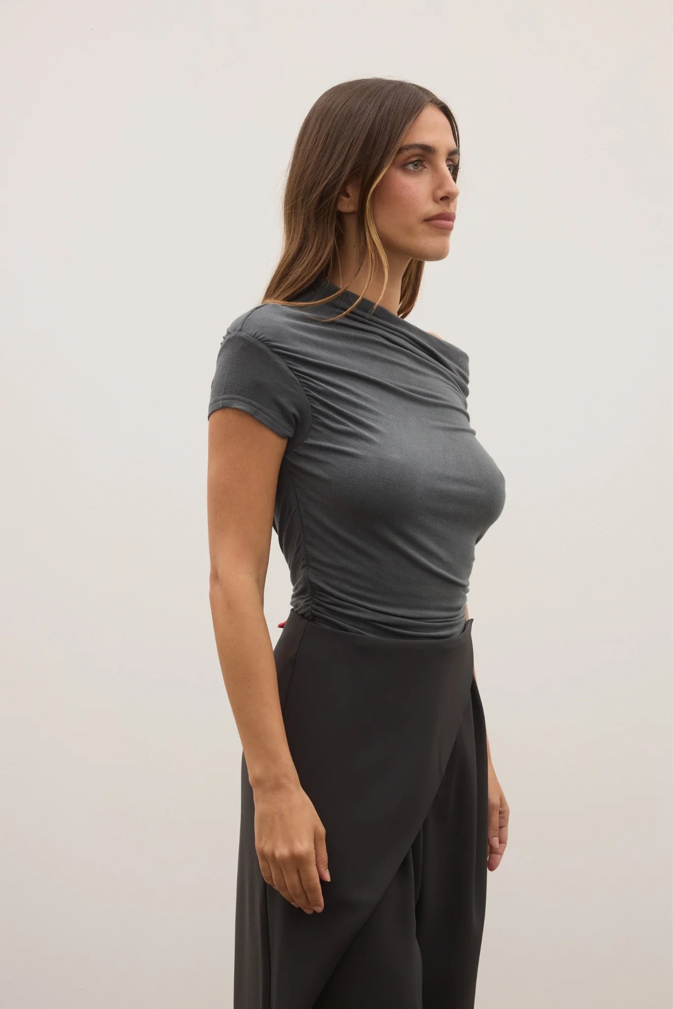 Woman wearing a gray top and black skirt against a white background