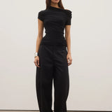 Woman wearing a black jumpsuit against a white background