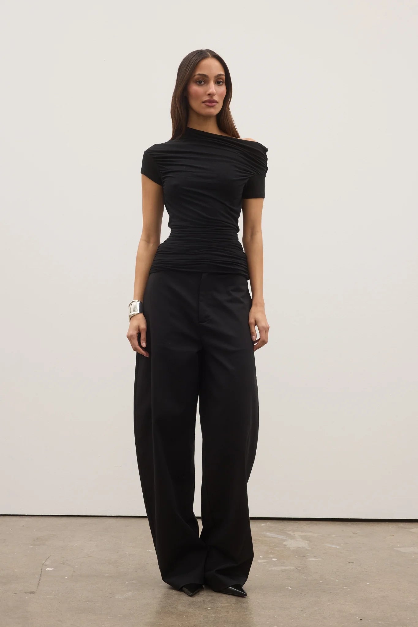 Woman wearing a black jumpsuit against a white background