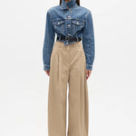 Person wearing a blue denim jacket and beige pants on a white background