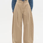 Person wearing beige wide-leg pants with a blue denim jacket on a white background