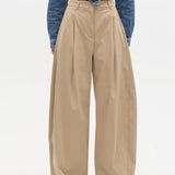 Person wearing beige wide-leg pants with a blue denim jacket on a white background